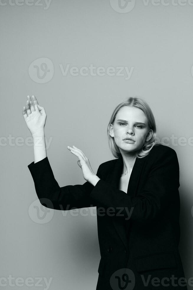 Fashion model girl posing with her hands up in the studio in black and white style in a classic jacket photo