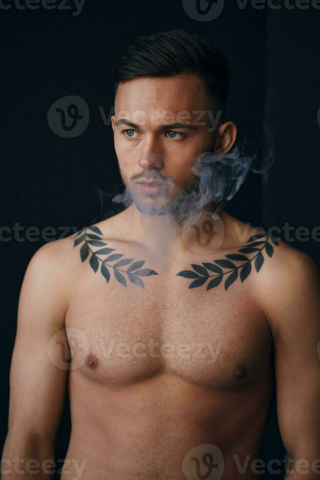 Modelling snapshots. Pensive serious tanned attractive handsome naked man thinking looks aside smoking posing isolated in black studio background. Fashion offer. Copy space for ad. Closeup photo