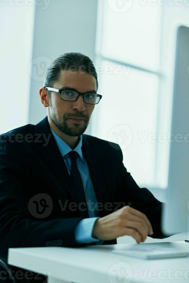 business man in a suit with glasses in the office at his desk photo