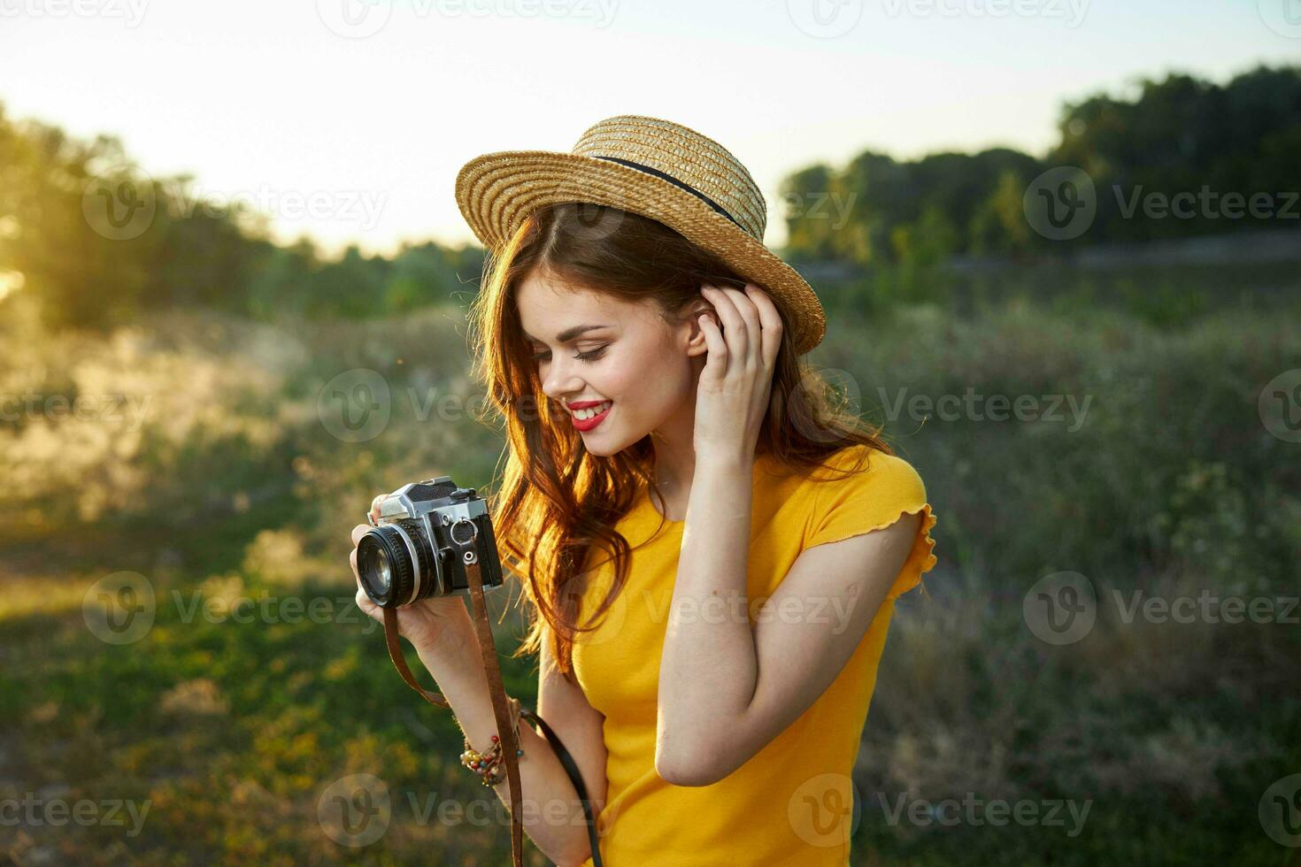 mujer participación un cámara en su manos sombrero endereza su pelo sonrisa rojo labios naturaleza foto