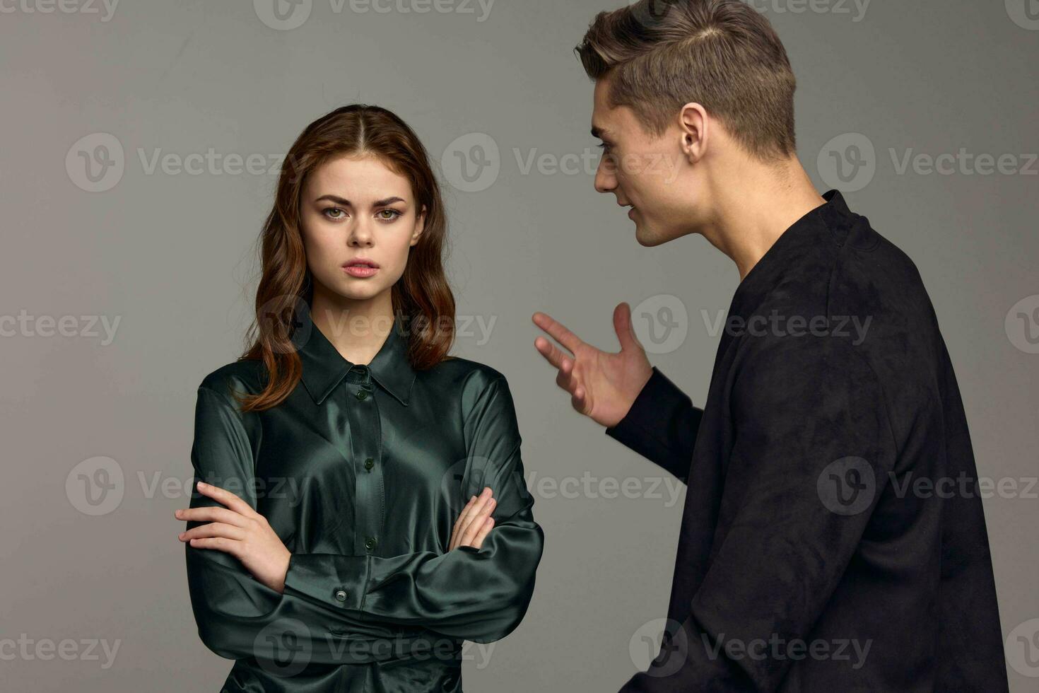 An indignant man in a black jacket gestures with his hands and looks at the woman photo