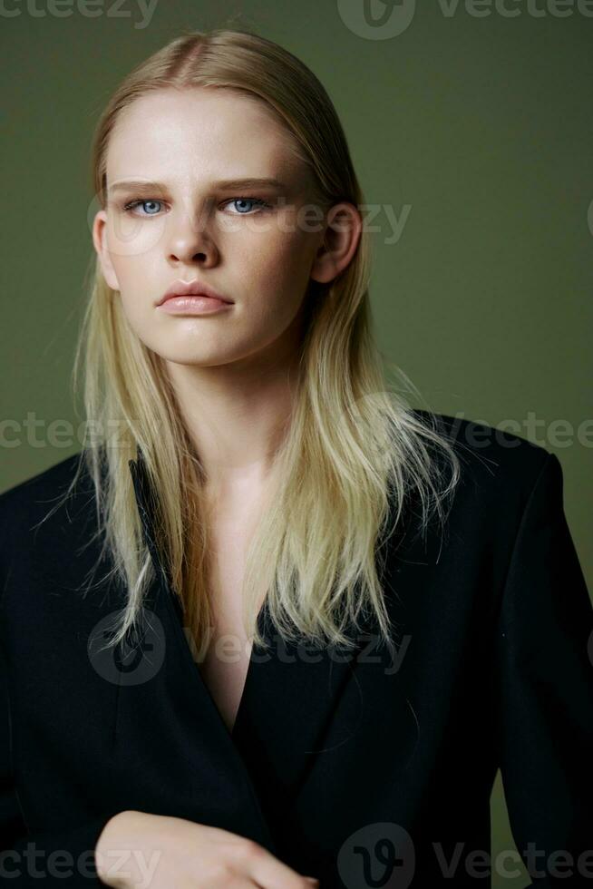 A close portrait of a beautiful lady in a suit posing on a green background photo