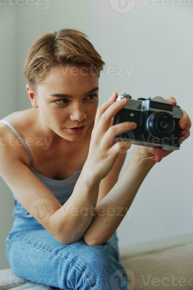 Woman photographer shooting in studio on old film camera at home on couch portrait, white background, free copy space, freelance photographer photo