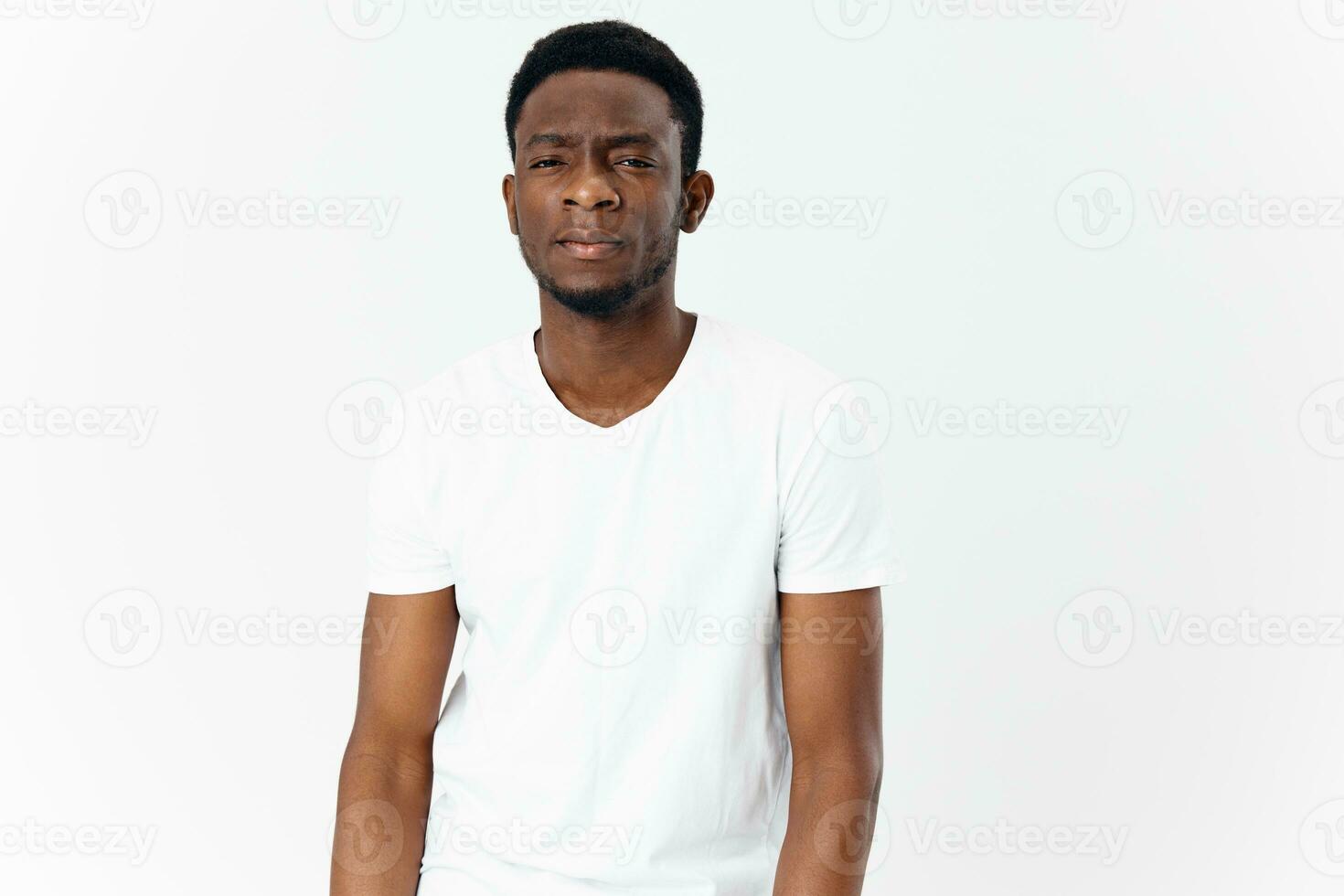 hermoso africano hombre en apariencia blanco camiseta en un ligero antecedentes retrato foto