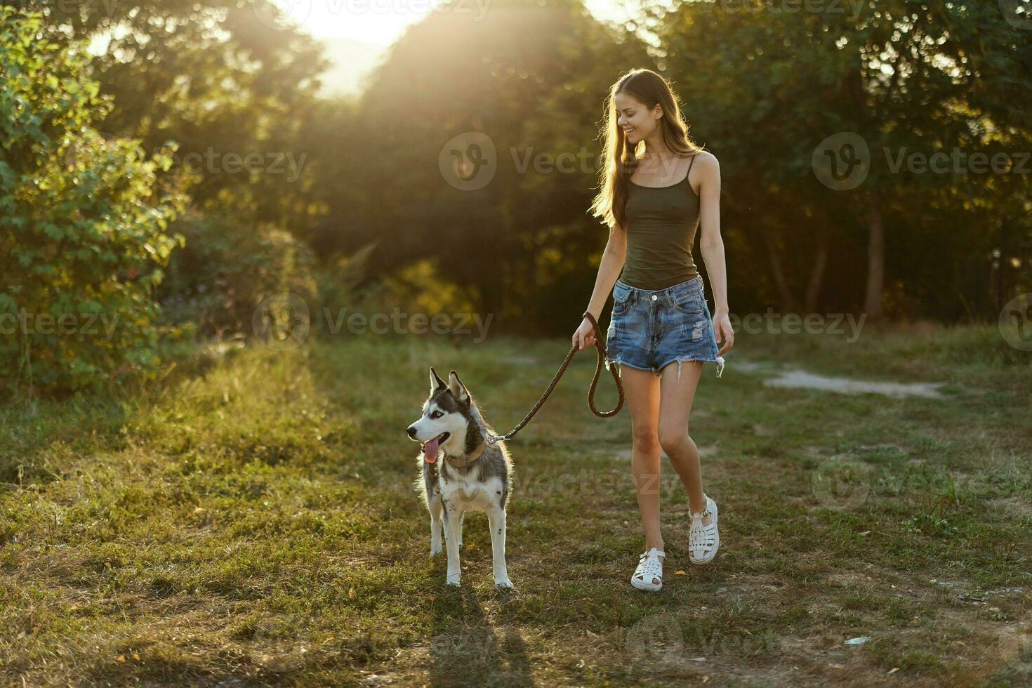 Woman and her husky dog walking happily on the grass in the park smile with teeth in the fall walk with her pet, travel with a dog friend photo