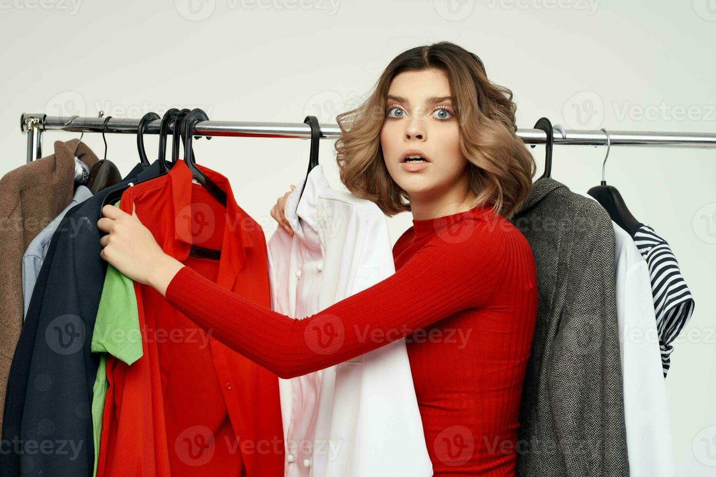 cheerful woman in a red jacket near the wardrobe light background photo