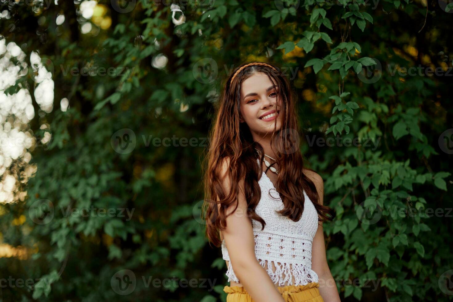 A woman in eco-friendly clothing in a hippie look dances in nature in the park and smiles at the world. The concept of harmony with the body and the surrounding nature photo