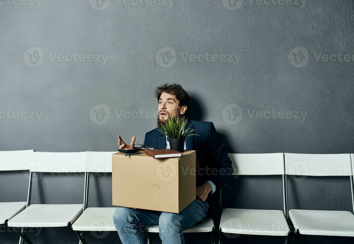 un hombre con cosas en un caja se sienta en un silla esperando para descontento foto