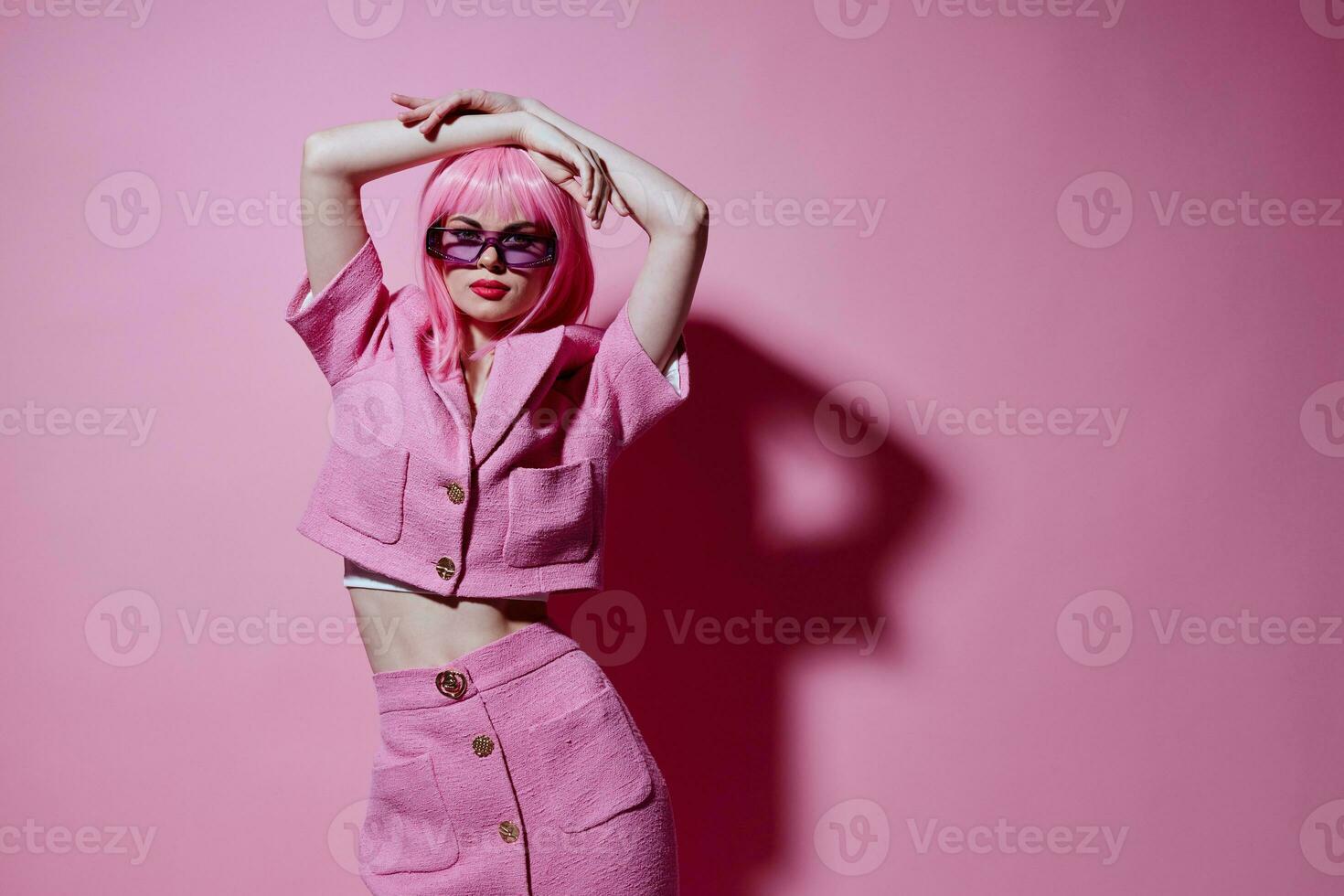 Young positive woman pink suit sunglasses posing pink background unaltered photo
