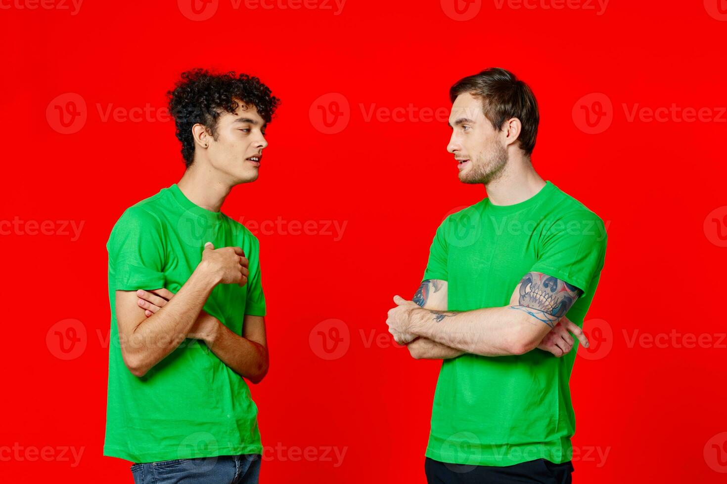 two friends in green t-shirts are standing side by side communication positive red background photo