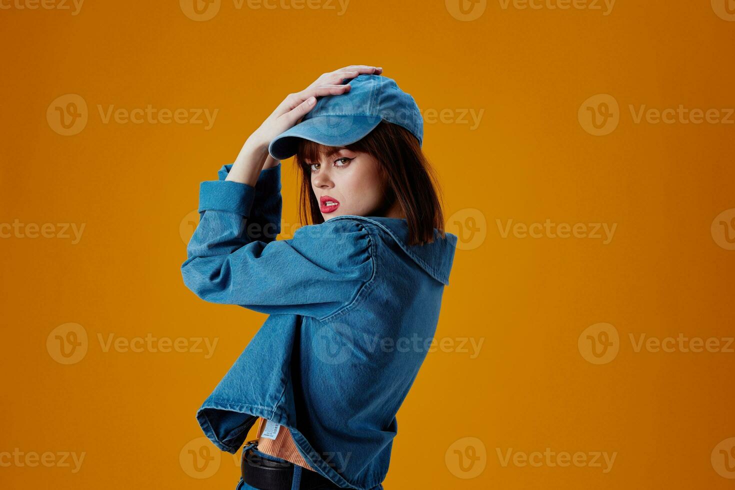 Portrait of a charming lady in a cap and denim jacket posing color background unaltered photo