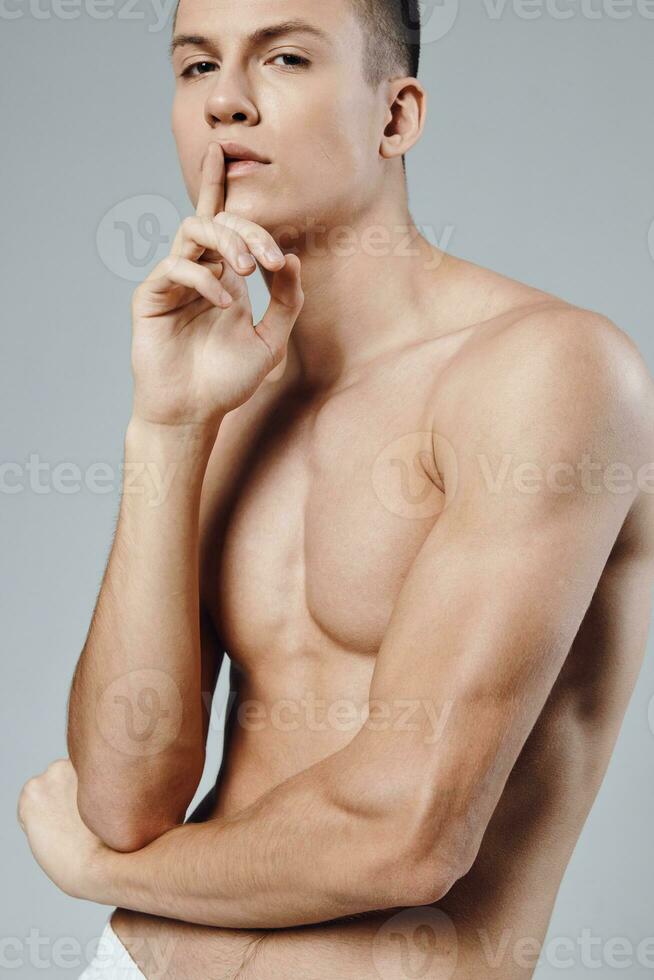 guy with a pumped up press holds a finger near the face on a gray background close-up photo