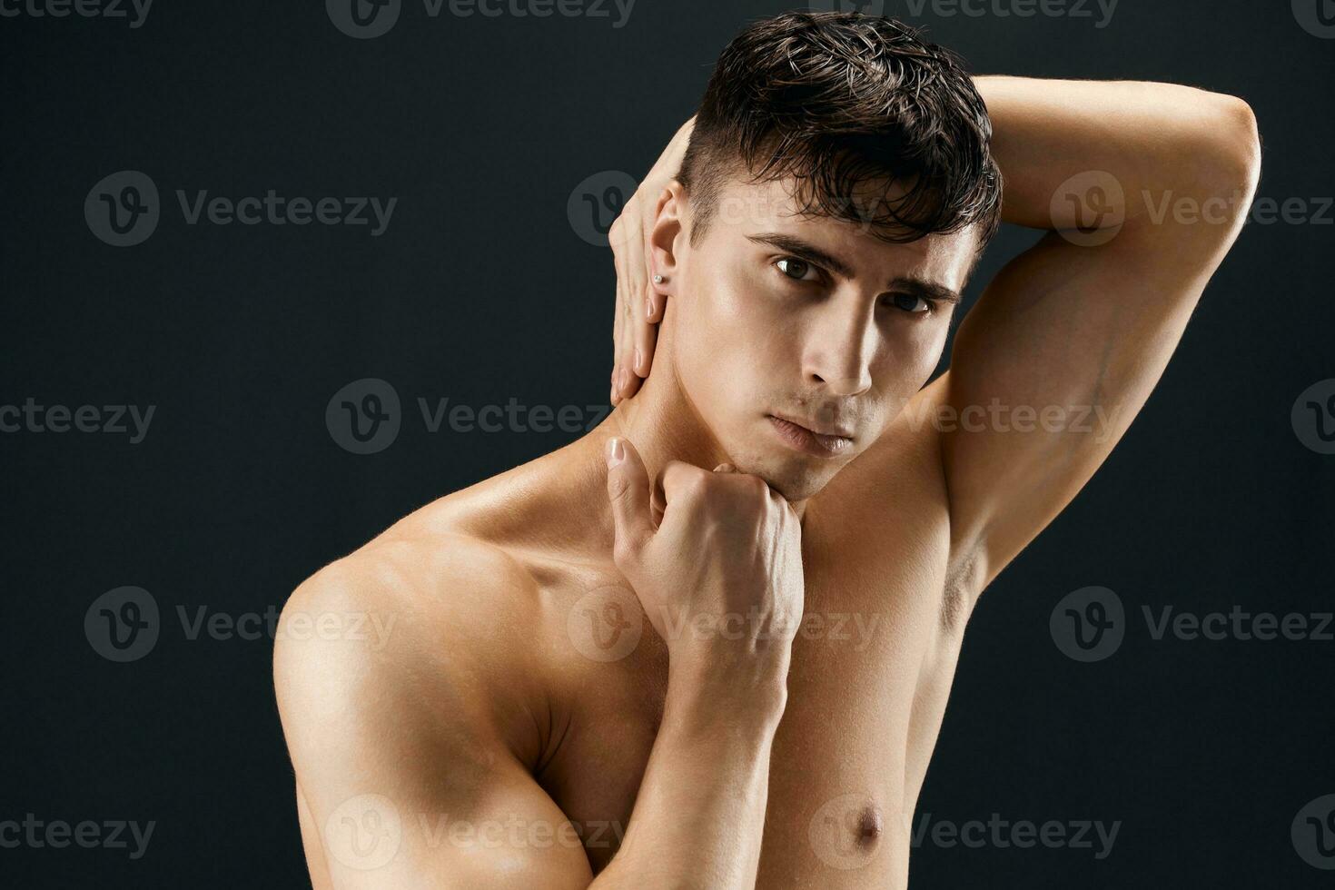 handsome male bodybuilder with a pumped-up body posing against a dark background photo