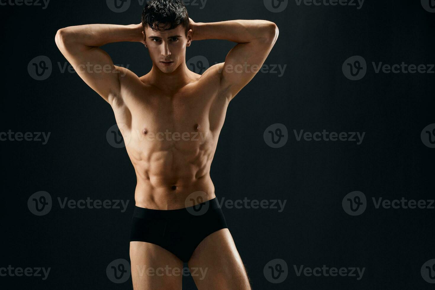 attractive sporty man with pumped up abs posing in dark studio panties photo