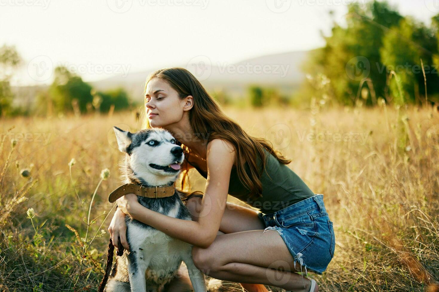 mujer sonriente y abrazando su perro sentado en un campo con un perro tejonero perro sonriente mientras gasto hora al aire libre con un amigo perro en otoño a puesta de sol mientras de viaje foto