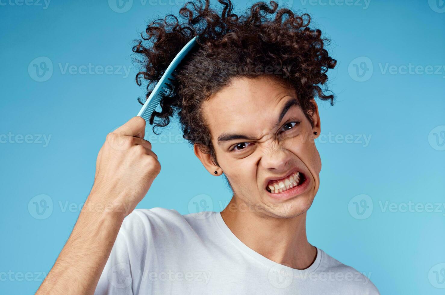 problems with combing hair young guy in t-shirt and combing curls model photo