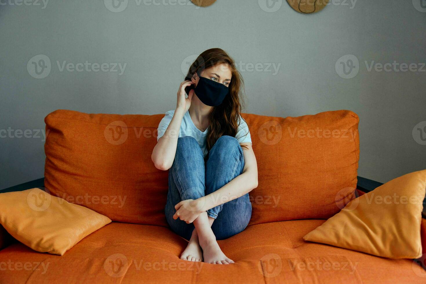 portrait of a woman sitting on the orange sofa at home in protective masks unaltered photo