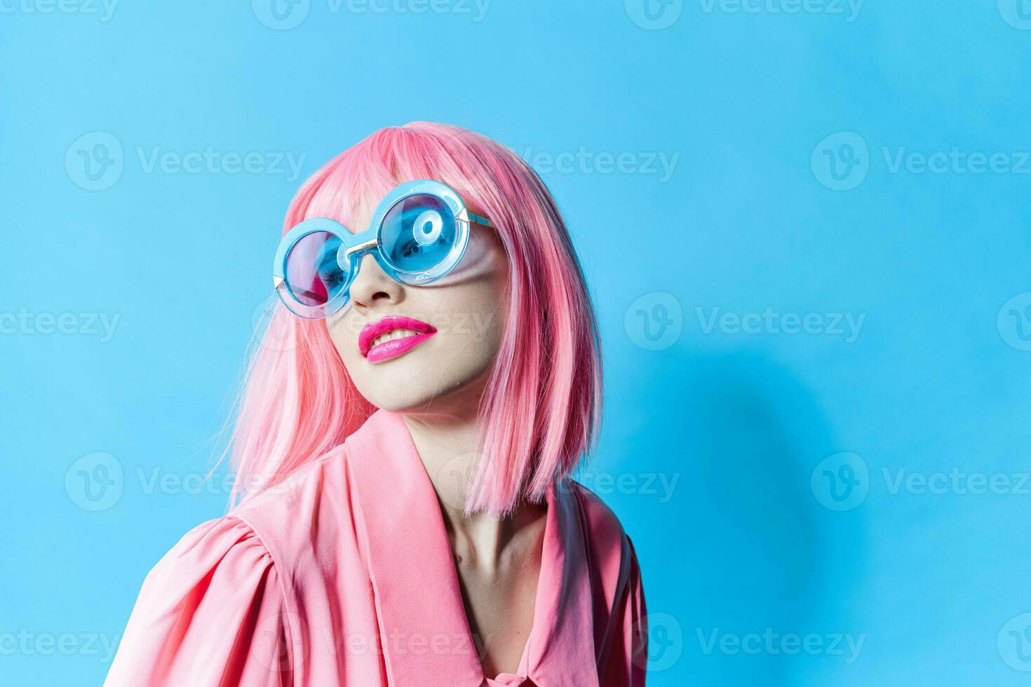 atractivo mujer en azul lentes usa un rosado peluca estudio modelo inalterado foto