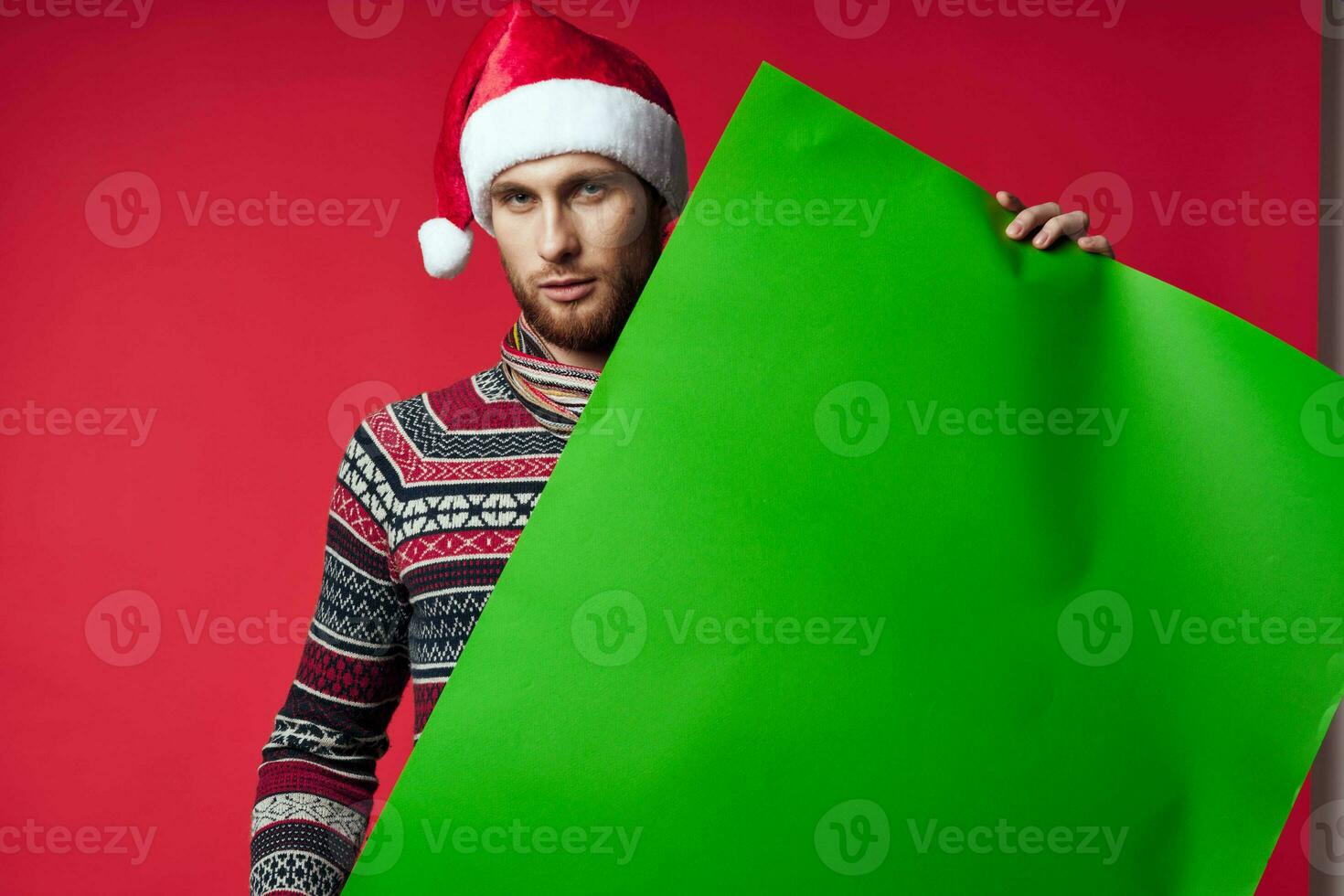 emotional man in a santa hat holding a banner holiday red background photo