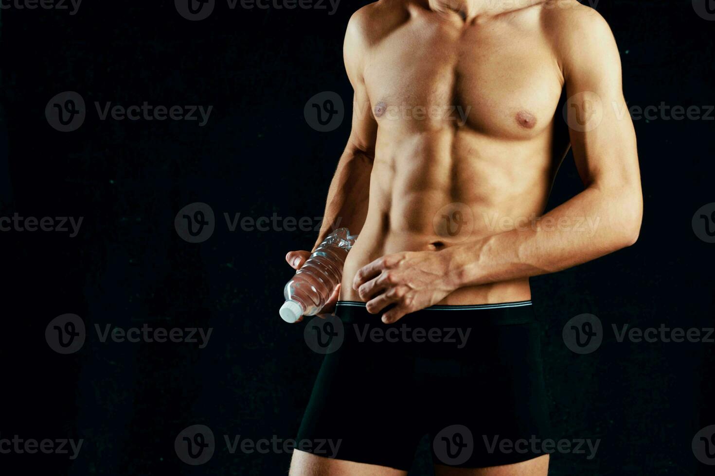 a man with a pumped up press in black shorts gym dark background photo