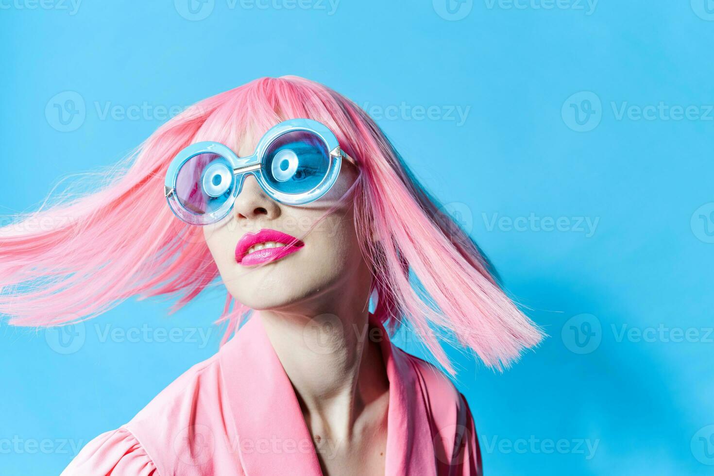 pretty woman in blue glasses wears a pink wig isolated background photo