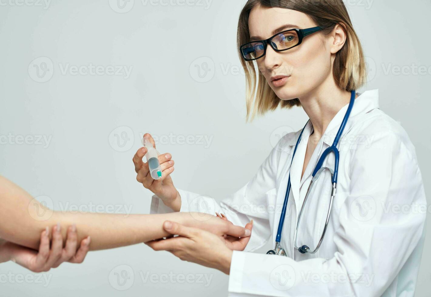 female doctor giving an injection to a scared female patient in a white t-shirt photo