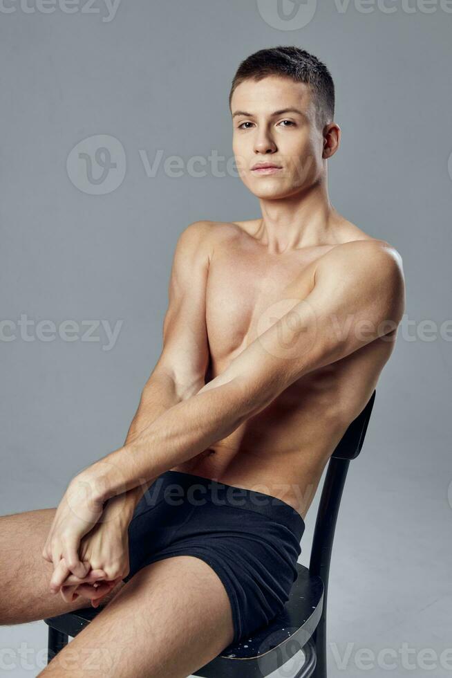 sporty man pumped up torso sitting on chair studio cropped view photo