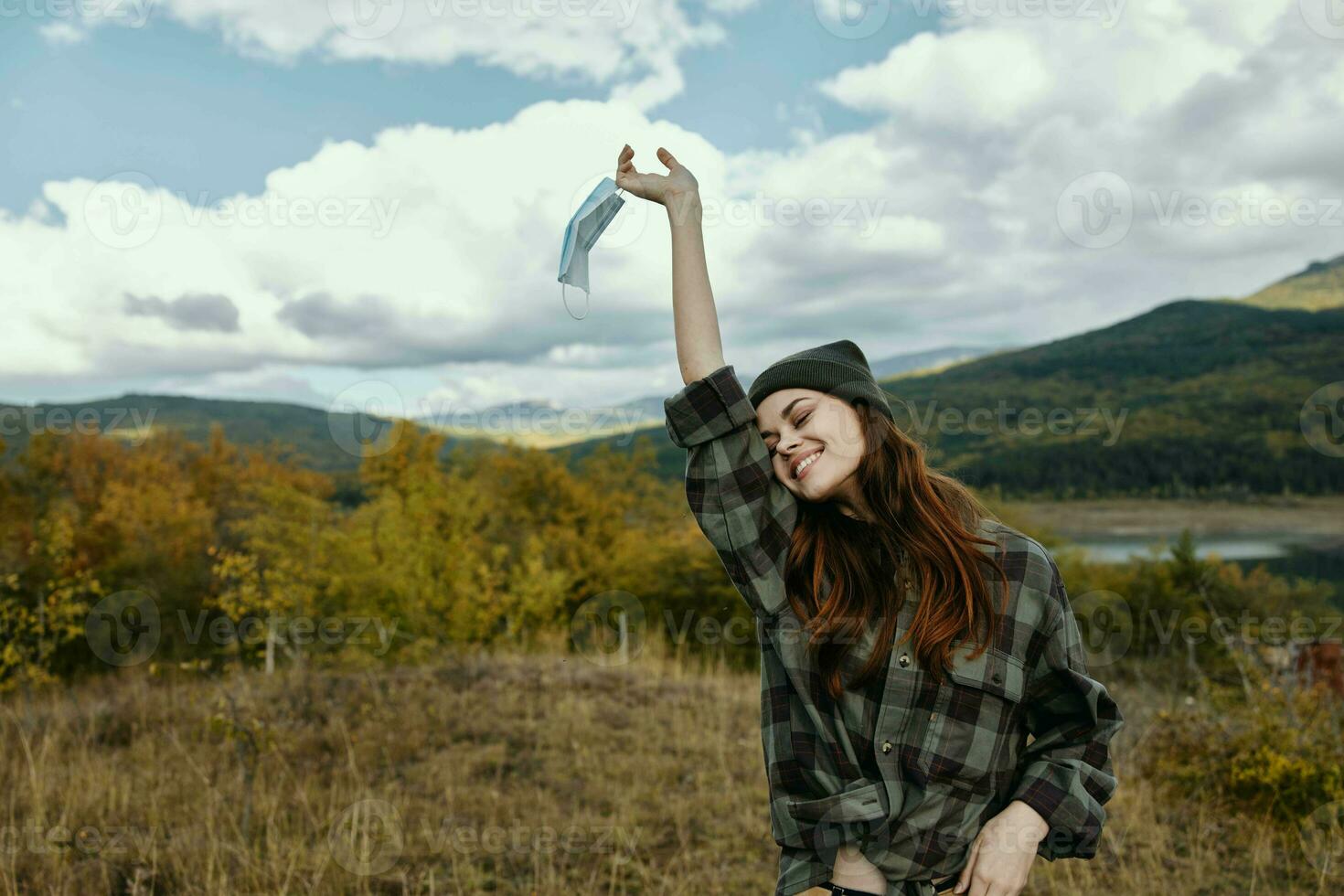 Happy traveler with a medical mask in hand is resting in nature in the forest photo