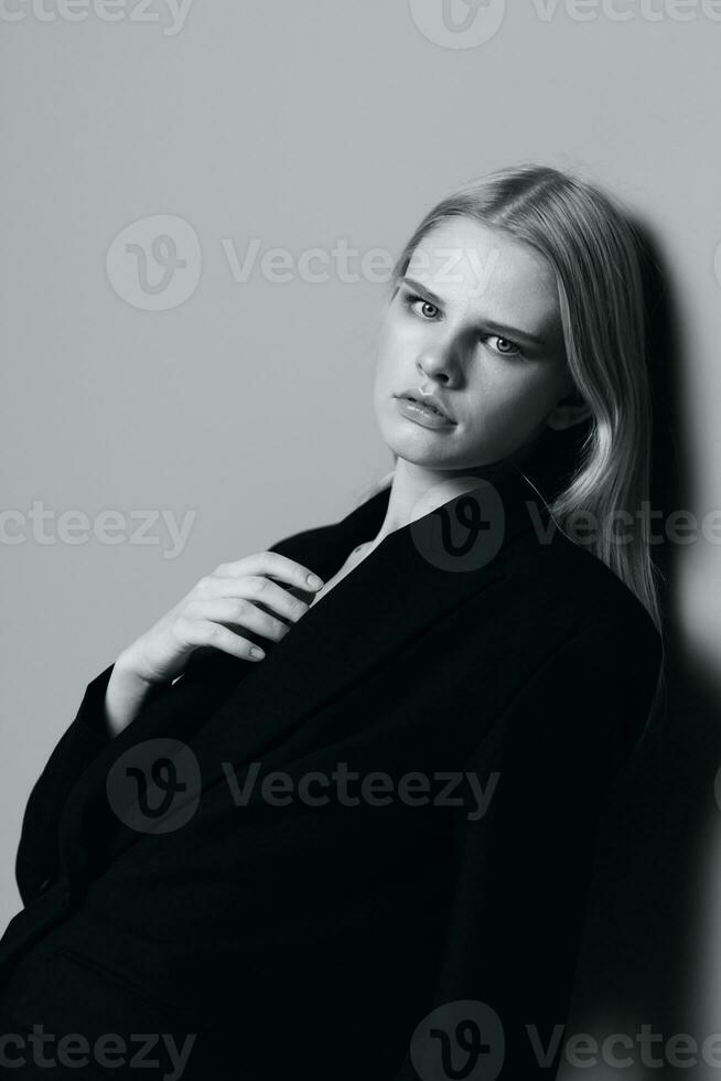 retrato de un hermosa rubia en un clásico chaqueta propensión en contra el pared en el estudio. negro y blanco estilo. concepto para ropa marcas foto