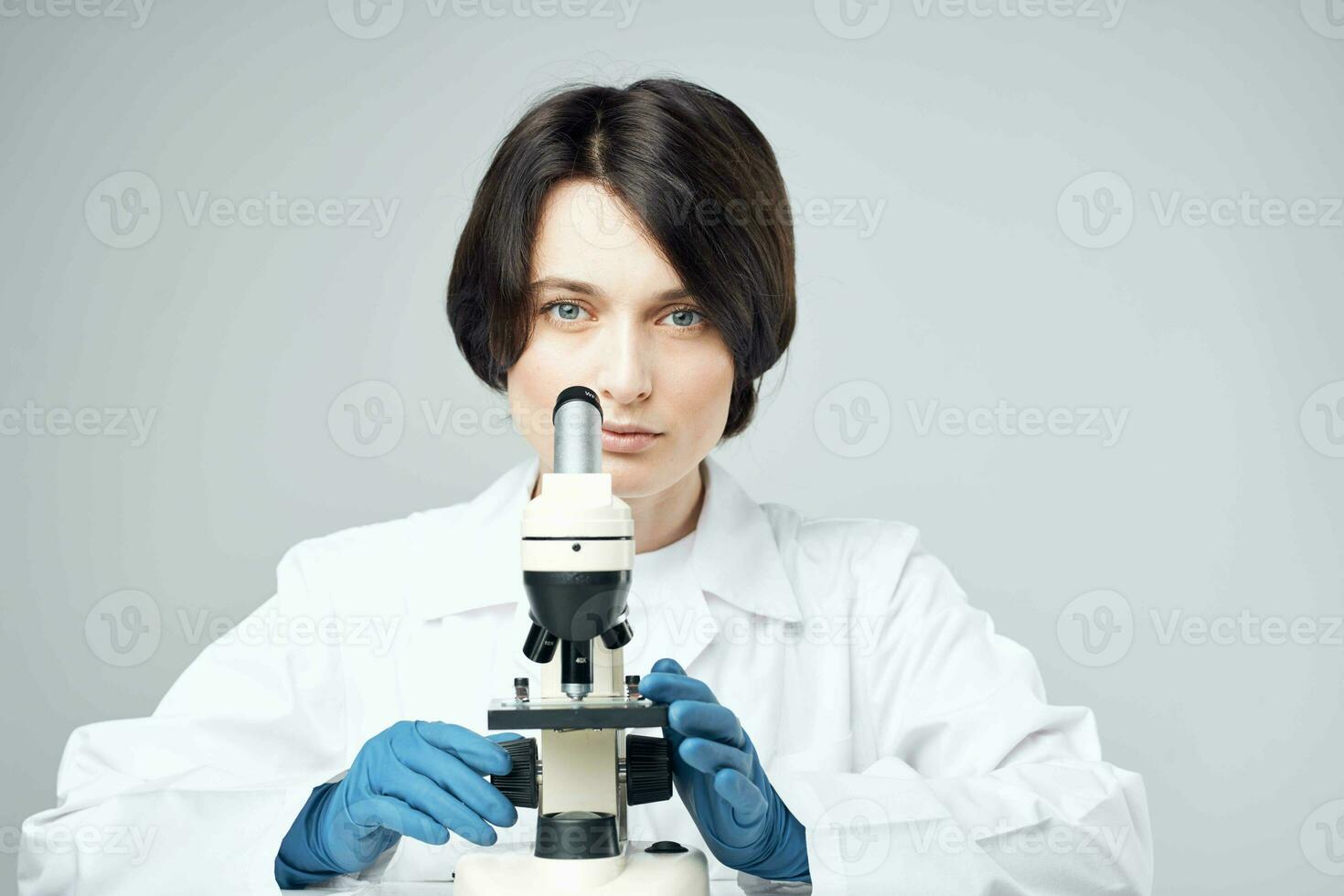 female laboratory assistant looking through a microscope diagnostics research science photo