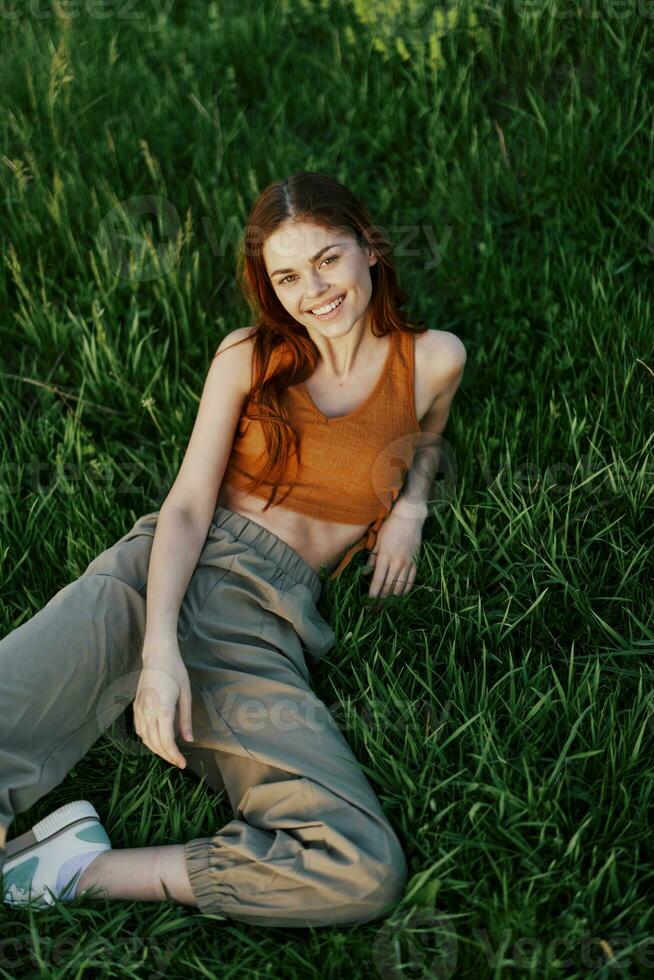 A young happy woman lying relaxed on the grass in the park, the lifestyle of a happy person without depression photo
