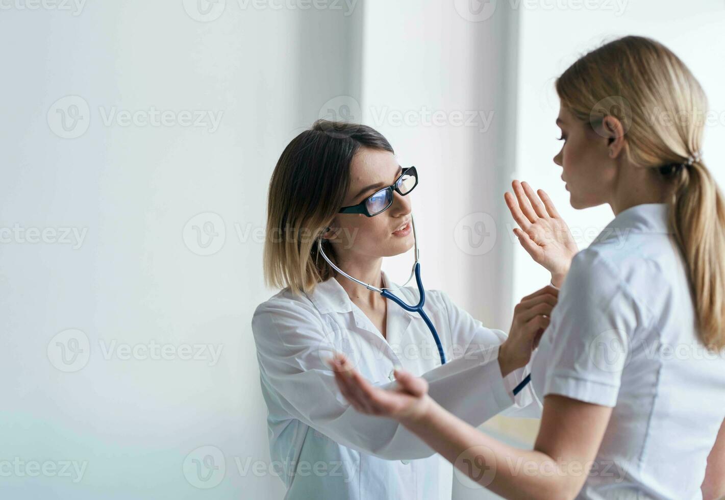 Woman doctor with stethoscope and glasses examines the patient health model photo