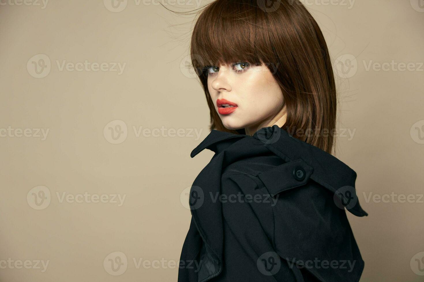 Pretty model dark coat good mood smiling on a beige background photo