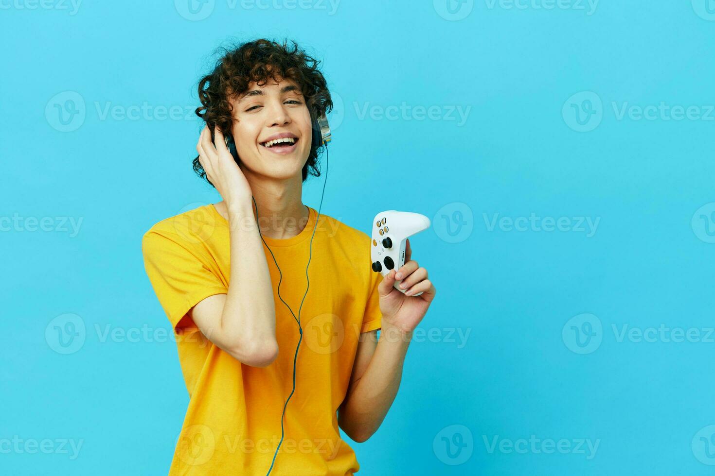 curly guy plays with joystick in yellow t-shirts technologies photo