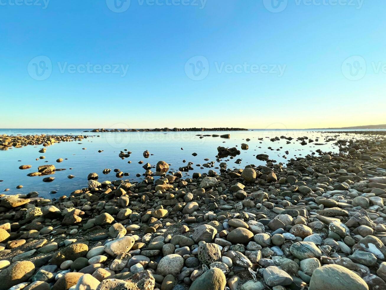 Rocky beach with calm sea and blue sky photo