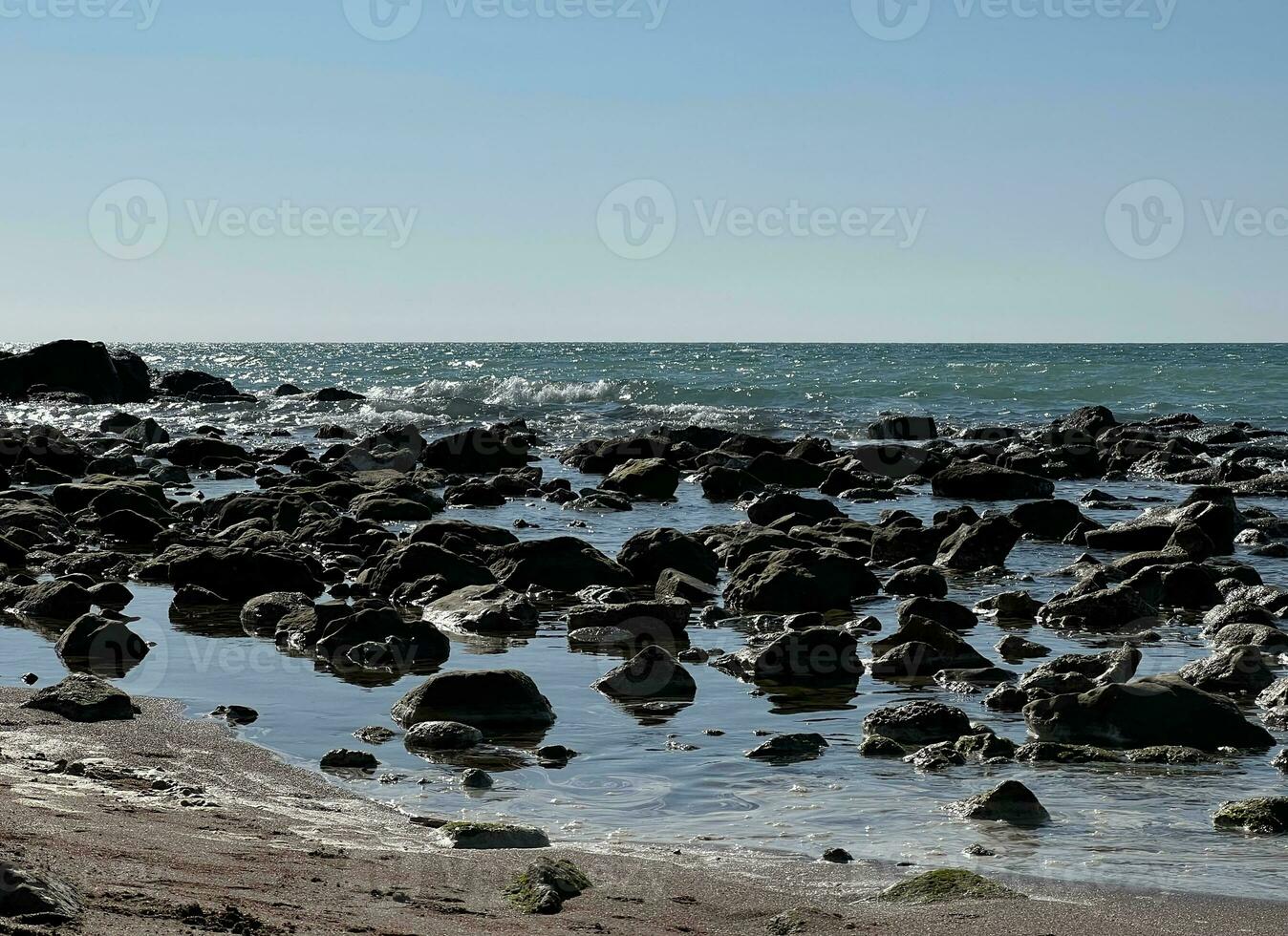 Rough sea with rocks on the beach photo