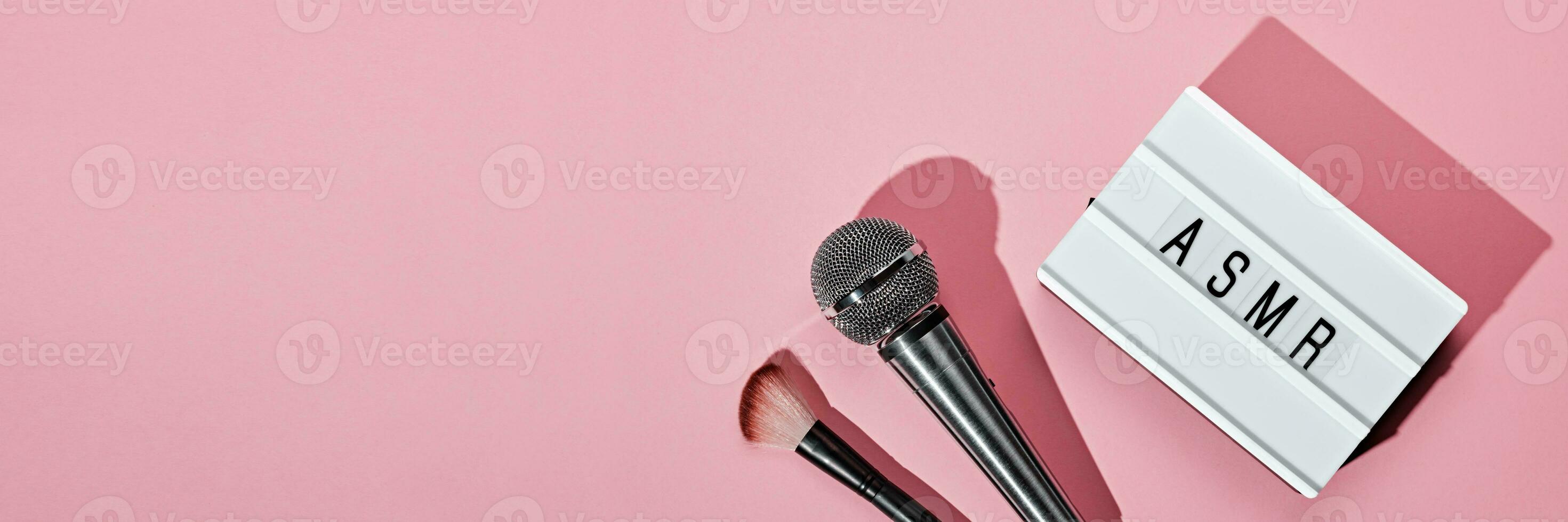 Microphone, brush and ASMR text lightbox on pink banner. ASMR recording stress relieving sounds concept, flat lay, trending shadows photo