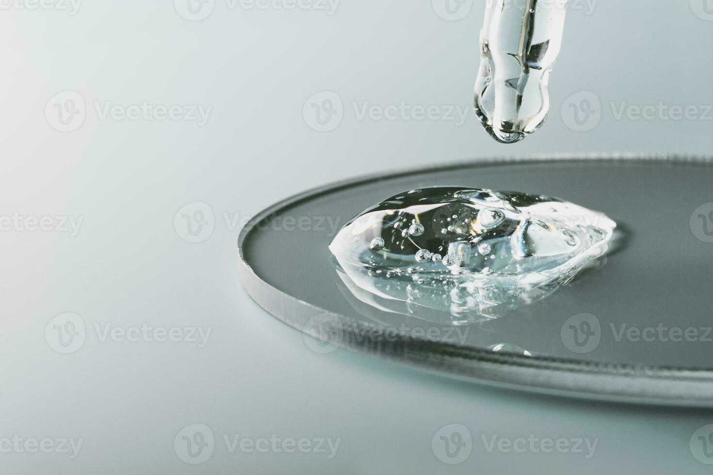 Pipette with sample of gels cosmetic product in petri dish on grey background, hard shadows, selective focus photo