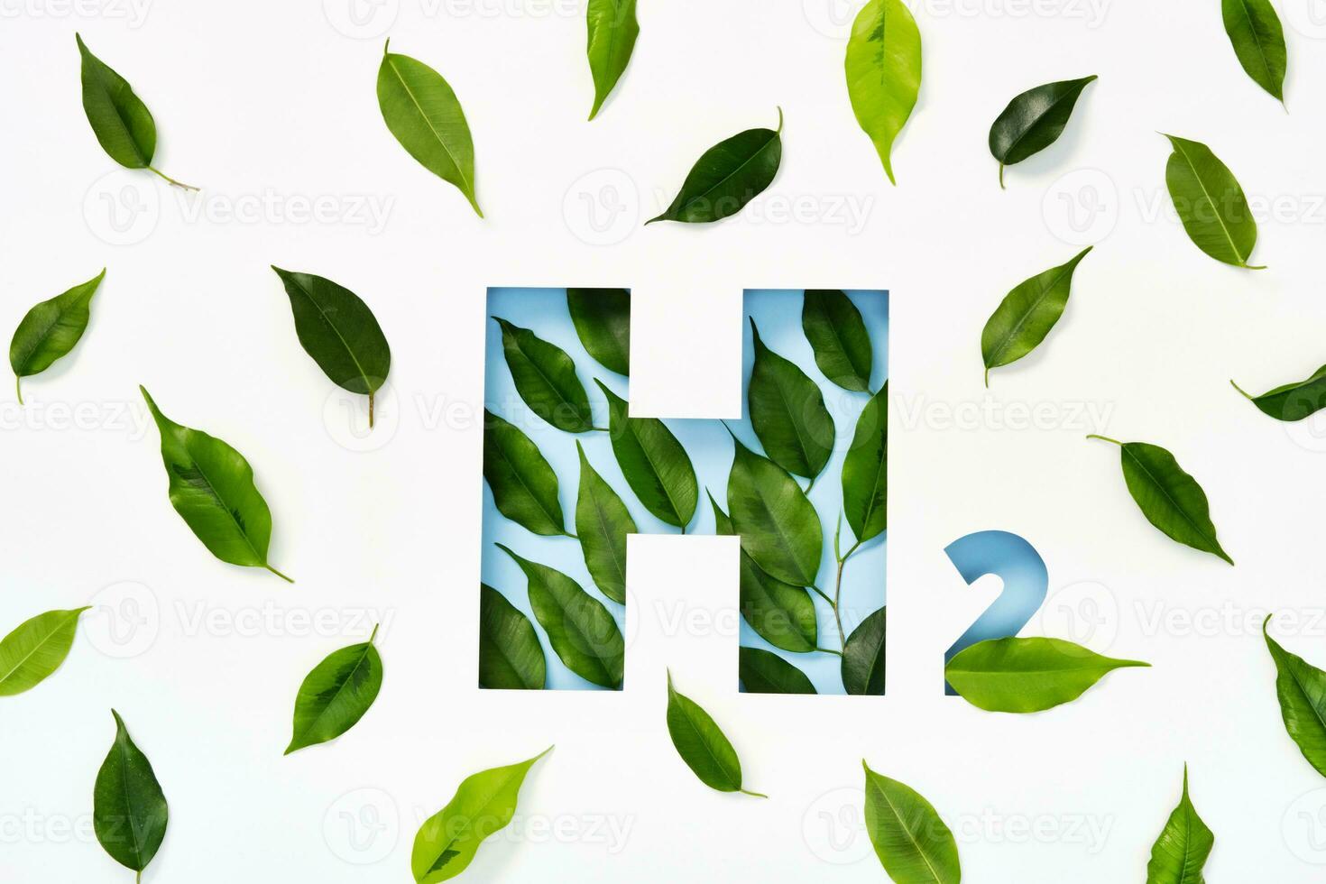 H2 hydrogen icon made of cut paper and green leaves on blue background. Emission-free biofuels concept photo