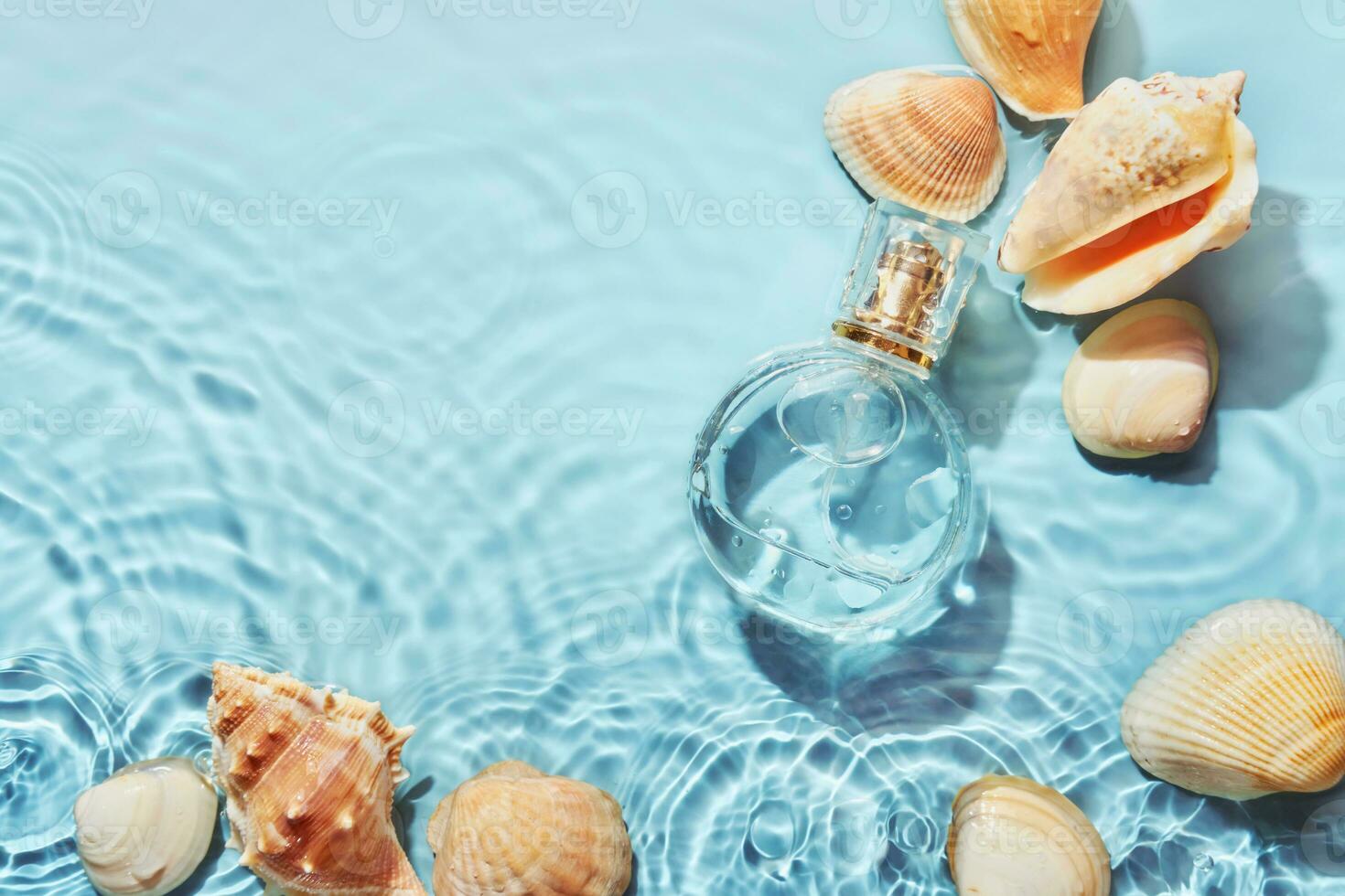 Glass perfume bottle and sea shells in spray water background. Marine