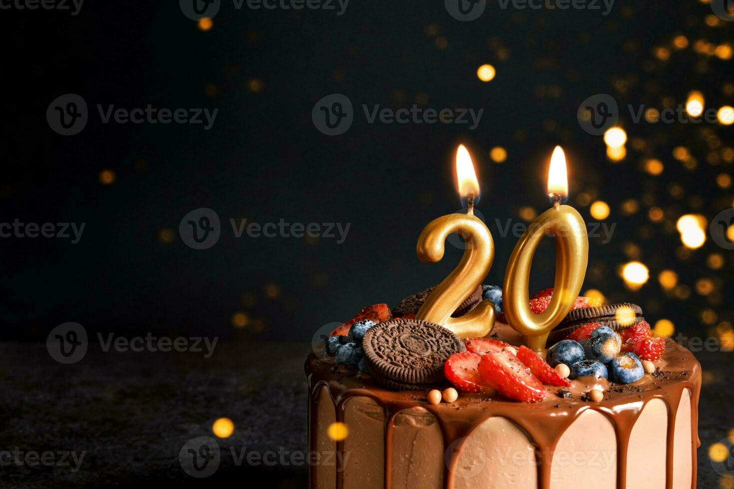 Chocolate birthday cake with berries, cookies and number twenty golden candles on black background, copy space photo