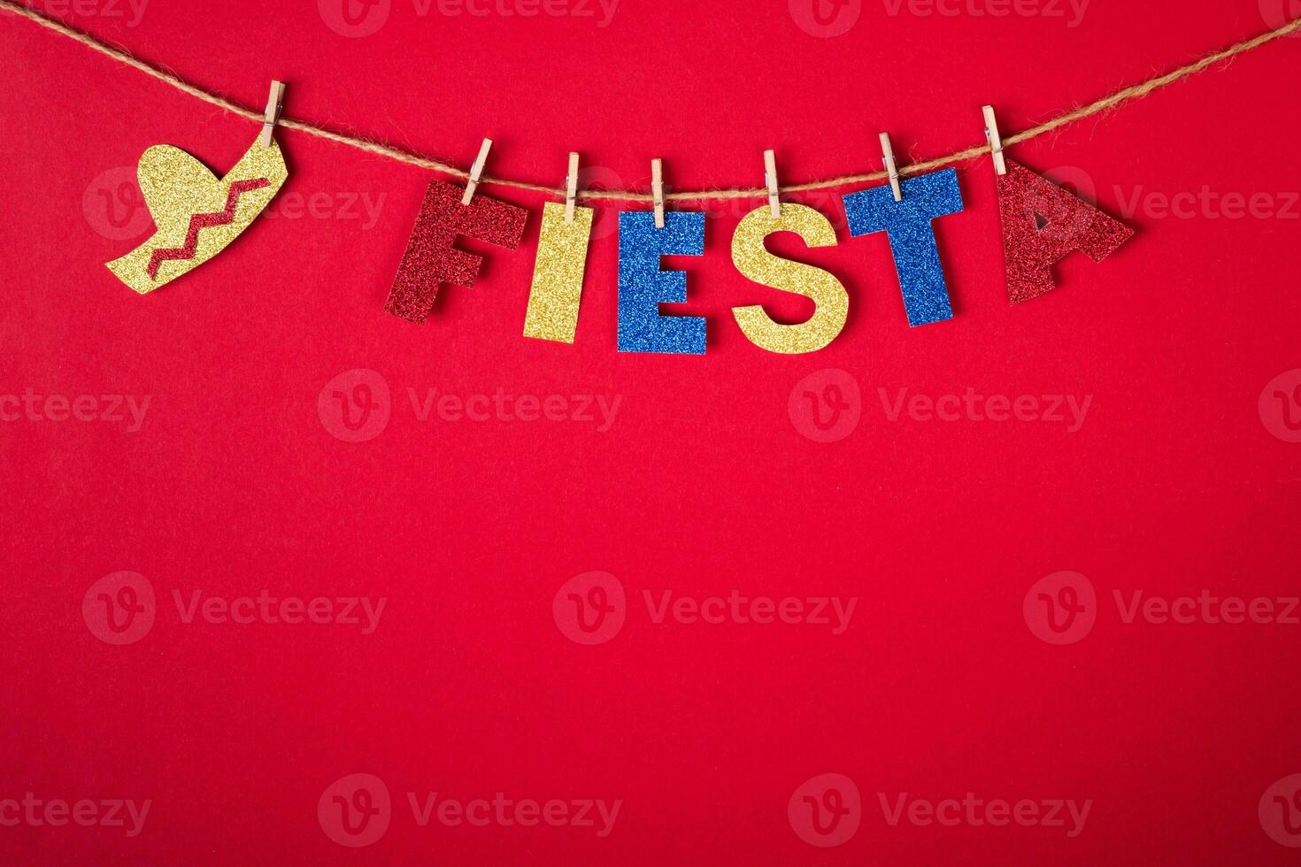 Fiesta word and sombrero on pins made of shiny paper on red background. Cinco de mayo concept photo