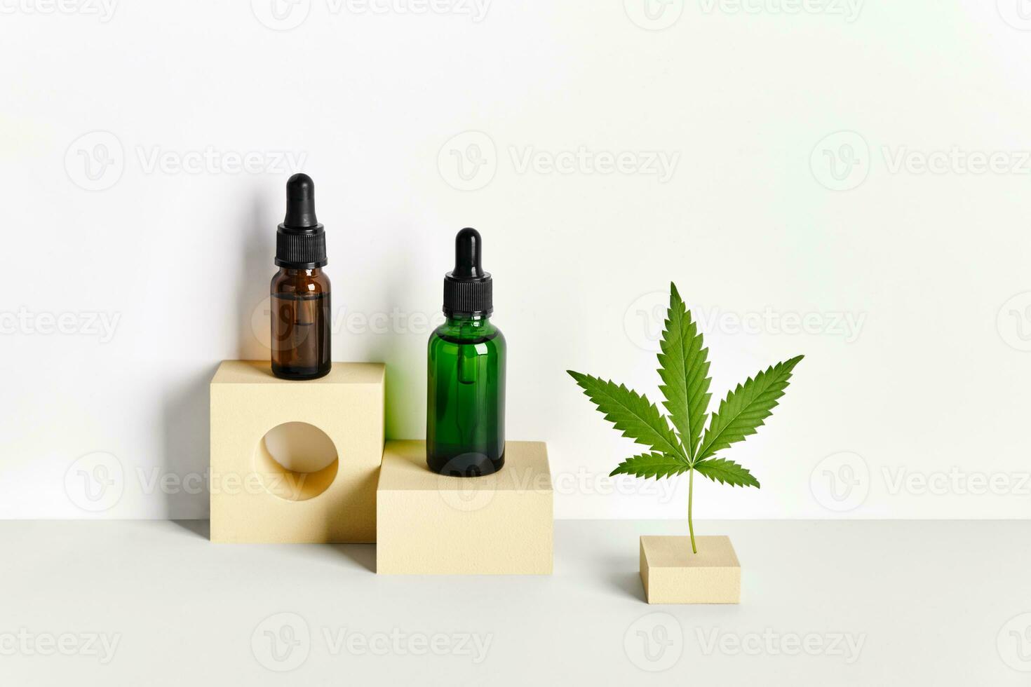 Cosmetic products with CBD oil and hemp extract. Glass bottles with pipette and hemp leaf on abstract geometric podiums photo