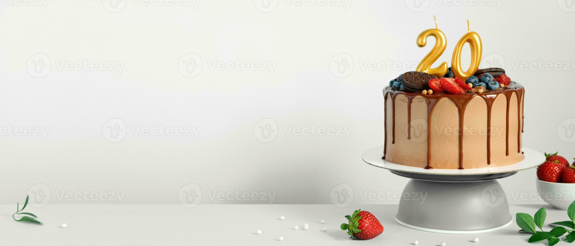 Banner with Chocolate birthday cake with berries, cookies and number twenty golden candles on White background, copy space photo