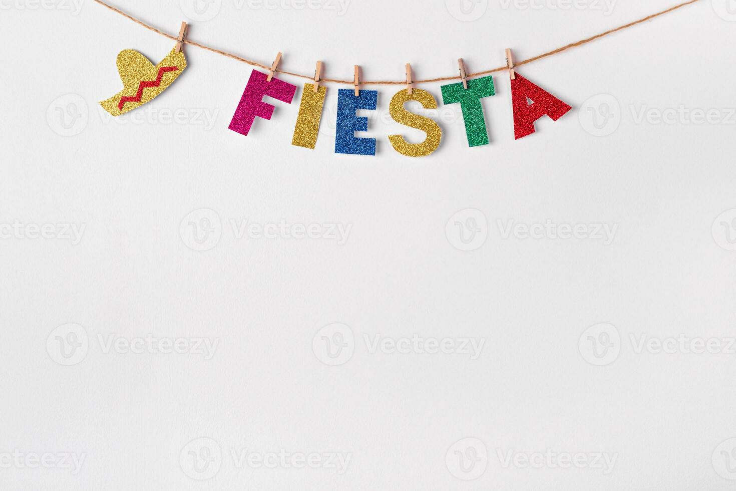 Fiesta word on pins against white wall background. Fragment of festive DIY decoration of interior. Cinco de mayo celebration photo