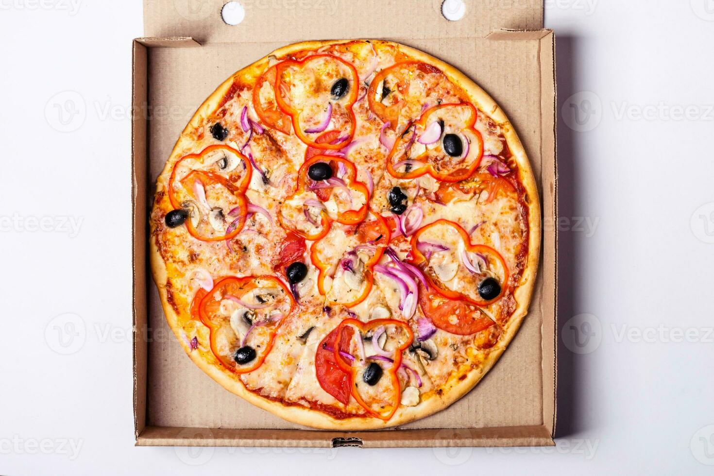 Vegetarian pizza with tomato, sweet pepper and olives in packing box on gray background photo