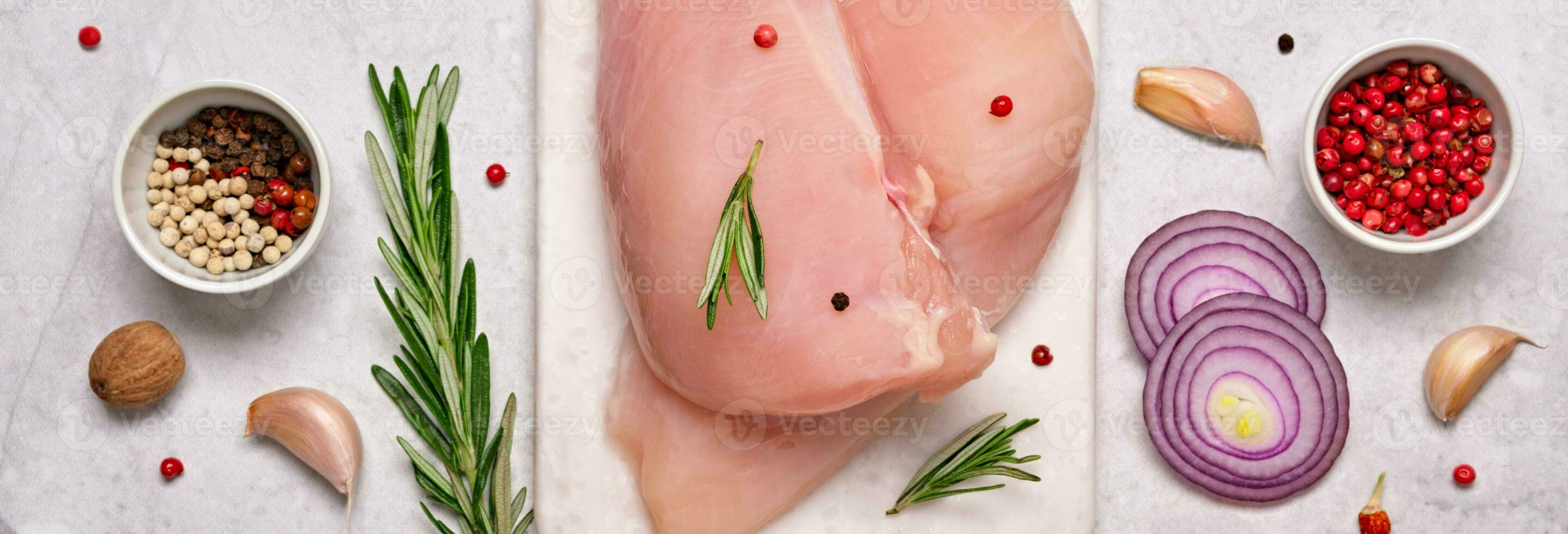 Fresh chicken breast fillet on cutting board with spices and herbs on gray marble background. Preparation for cooking, banner format photo