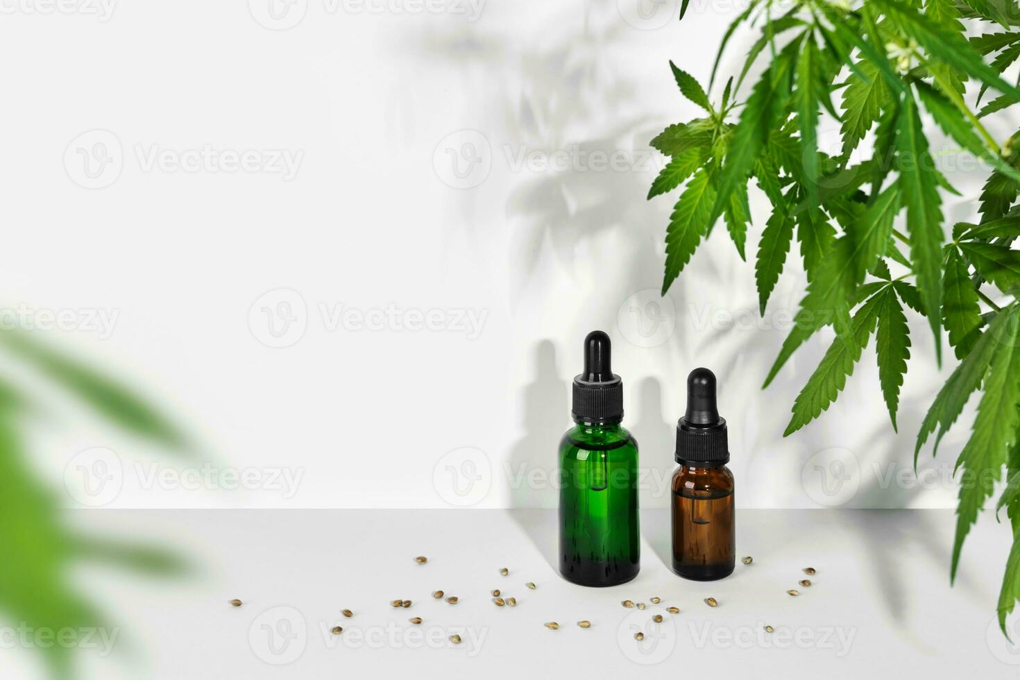 Cosmetic products with CBD oil and hemp extract. Glass bottles with pipette, hemp plant and seeds on table wall background photo