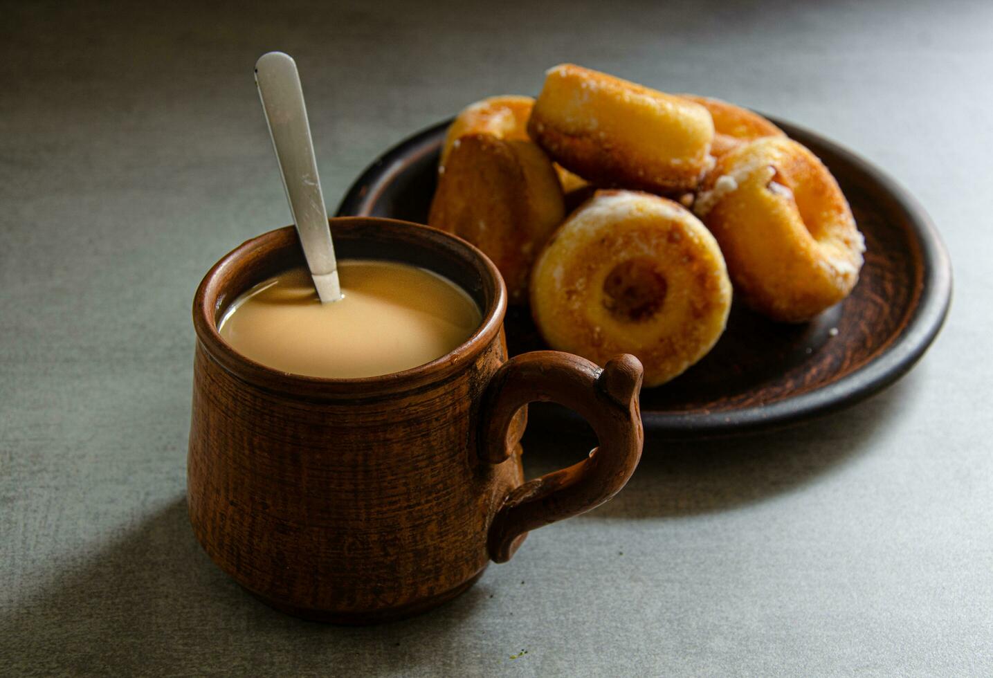 The most delicious homemade donuts and coffee with milk in a folk mug. Home cooking. photo