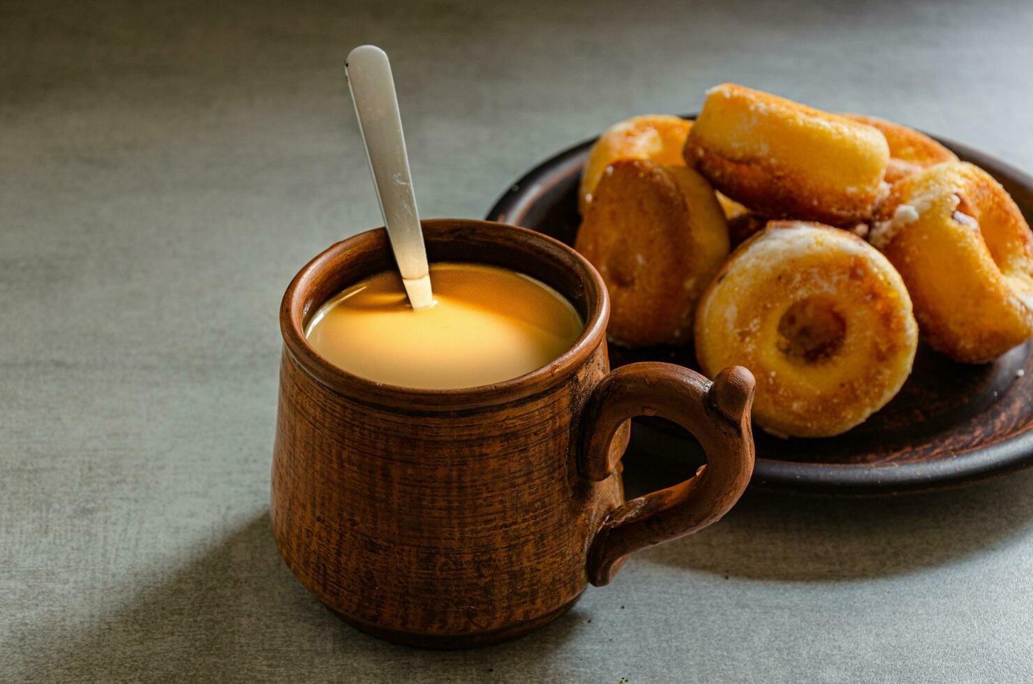 The most delicious homemade donuts and coffee with milk in a folk mug. Home cooking. photo